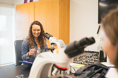 Student smiling at microscope